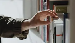 Person selecting a book from a shelf