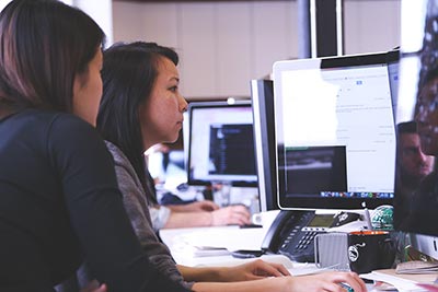 Two female students look at a computer monitor