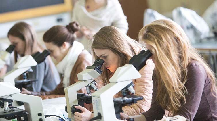 Female students looking through magnifiers