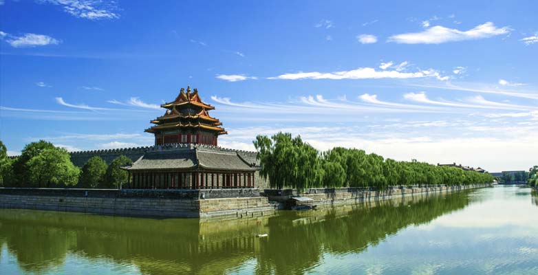 Traditional Chinese temple with red details surrounded by water with bright blue sky