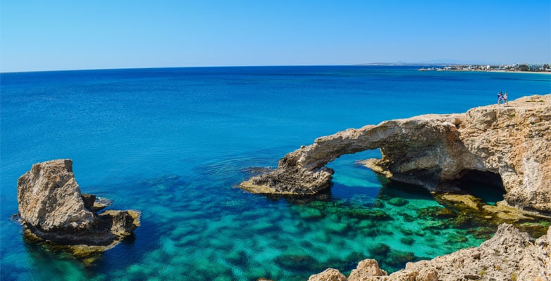 The Love Bridge, a rock formation with a backdrop of bright blue sky and deep blue sea
