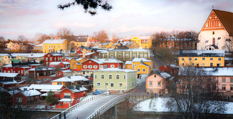 Brightly coloured, traditional Finnish houses in a light covering of snow