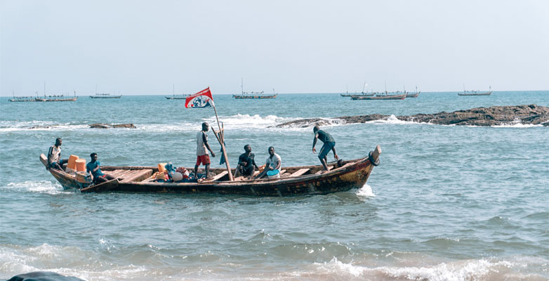 Six men in a boat off of the coast of Elmina, Ghana