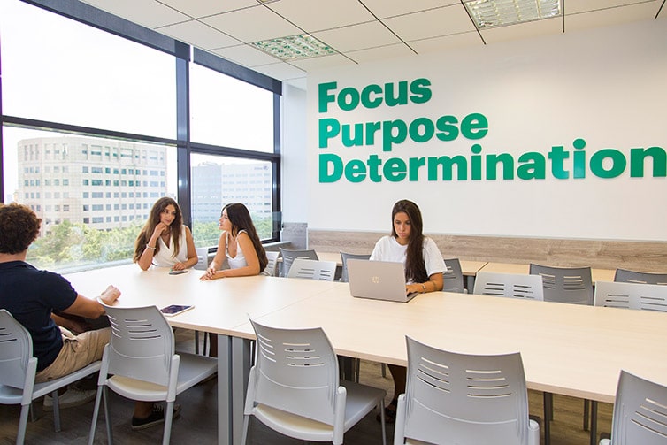 Students sitting at bright white desks with laptop