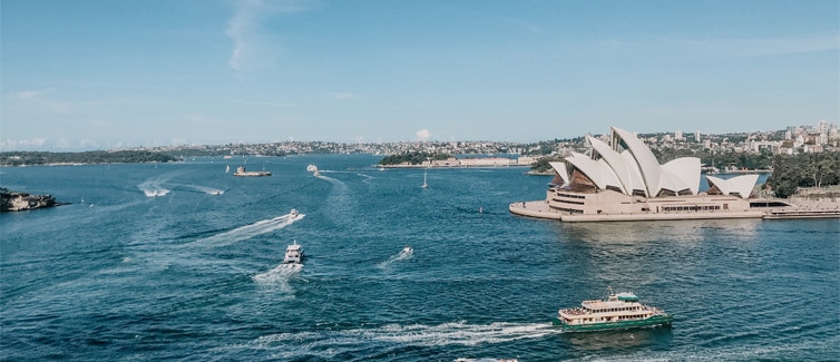 The Sydney Opera House next to a body of water with boats on it