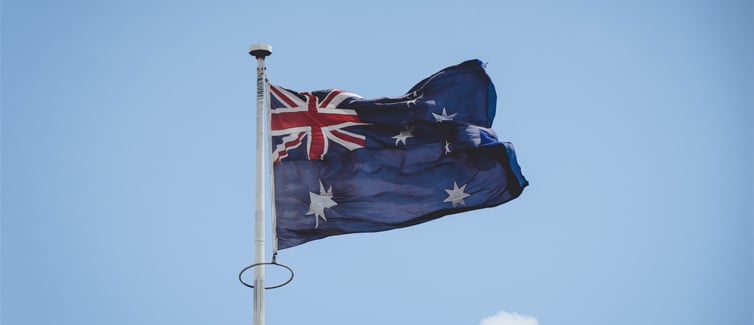 Image of the Australian flag flying on a flagpole with the blue sky in the background