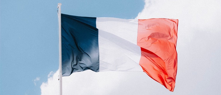 Image of the French flag flying on a flagpole with a light blue and white background
