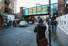 Small image of a person looking away from the camera and towards a bridge that has the words Camden Lock painted on the side