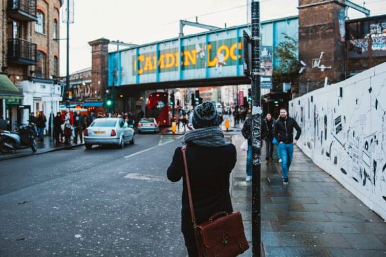 Image of a person looking away from the camera and towards a bridge with the words Camden Lock painted on the side