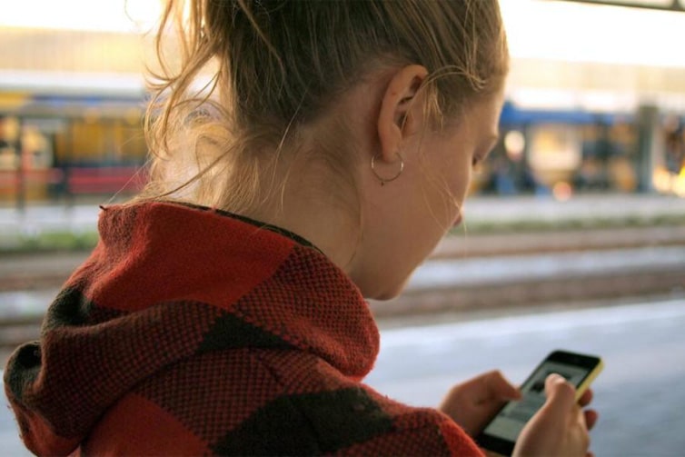 Person looking down towards their phone screen facing away from the camera