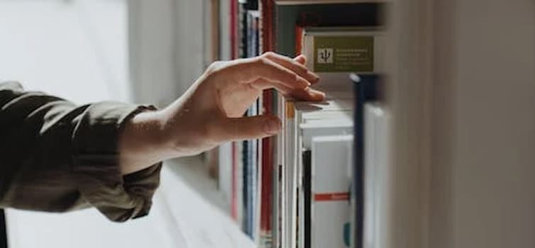 Person selecting a book to read at a library