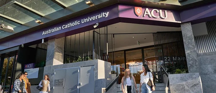 A group of students stood outside of a building that says 'Australian Catholic University' on it