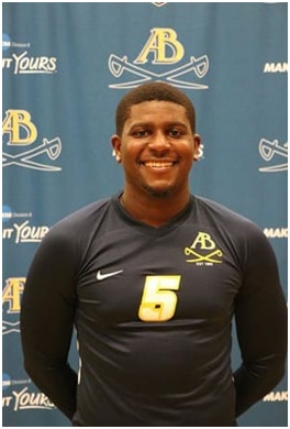 A student wearing a sports jersey with the number 5 on the chest smiling at the camera
