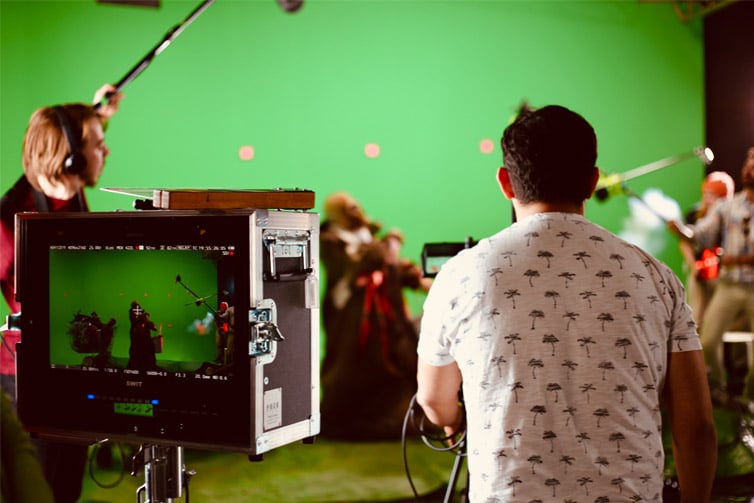 Several students with their backs to the camera, working with video production equipment