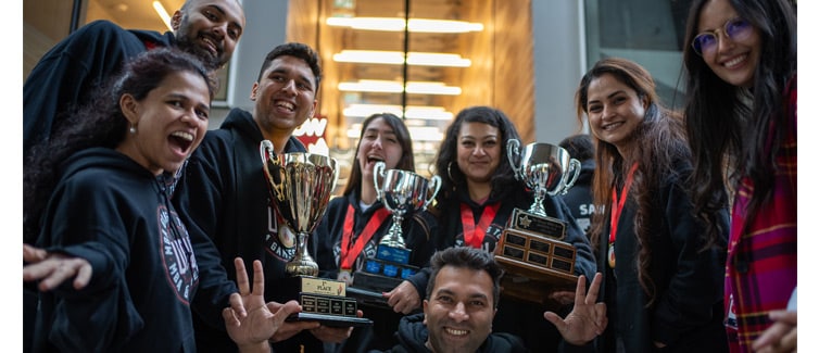 Image of students holding trophies and smiling at the camera