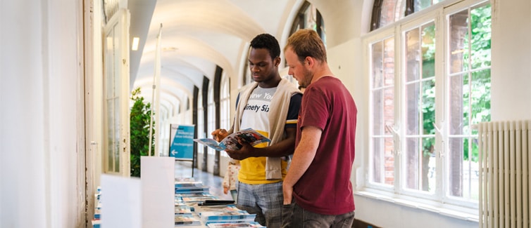 Image of two students looking at books on a table
