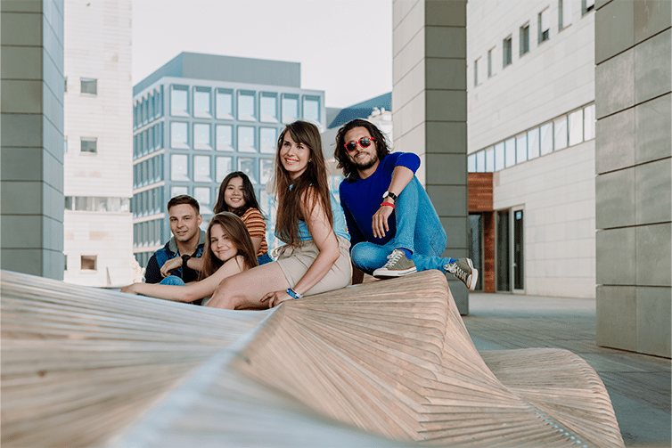 Image of a group of students sat on a decorative bench smiling at the camera