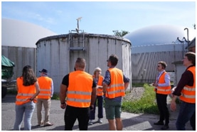 Image of students wearing hi-vis vests looking at large round structures