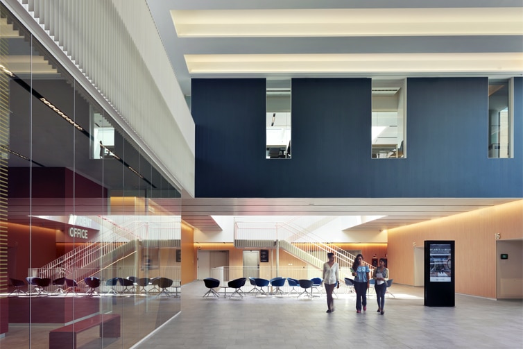 Image of three students walking through a large, light-filled atrium