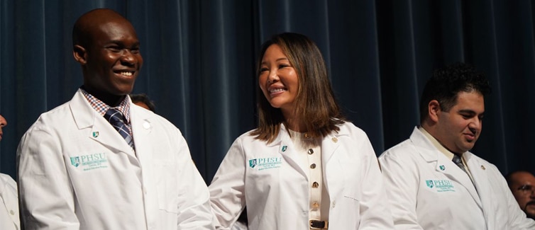 People wearing white medical coats smiling at each other.