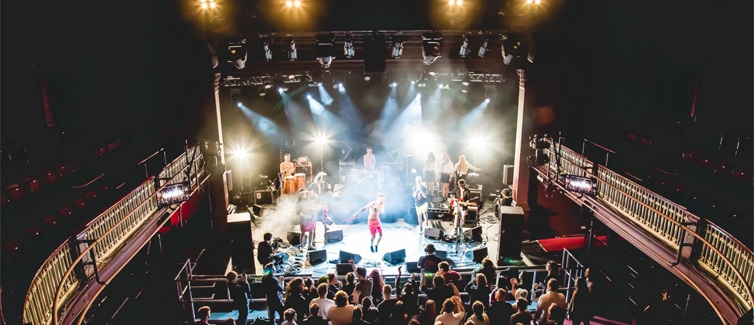 Image of a stage performance with bright lights and people on the stage
