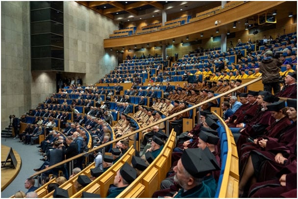 Theatre seats filled with people wearing caps and gowns in different colours